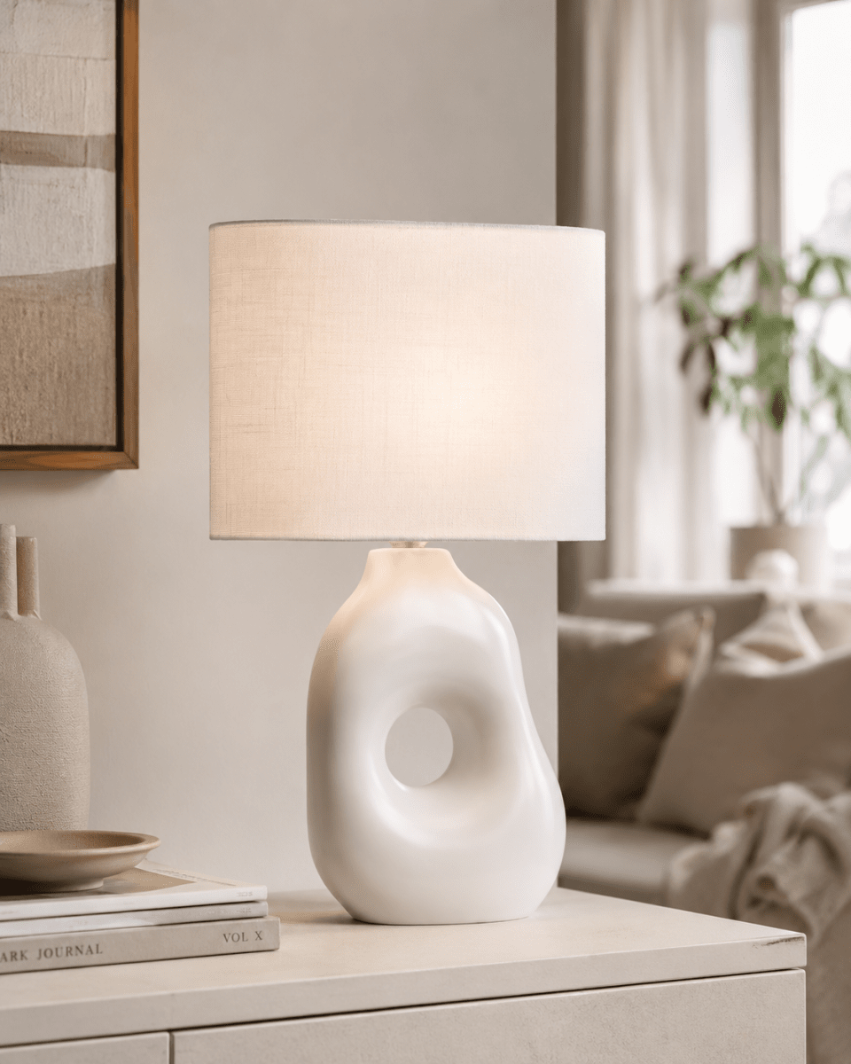 Pikazo 45cm Blanc lampe de table De Lampan - La lampe de table Pikazo s&eacute;duit par son pied sculptural unique en c&eacute;ramique orn&eacute; d'un motif de cheveux continu et son abat-jour ovale en lin blanc.