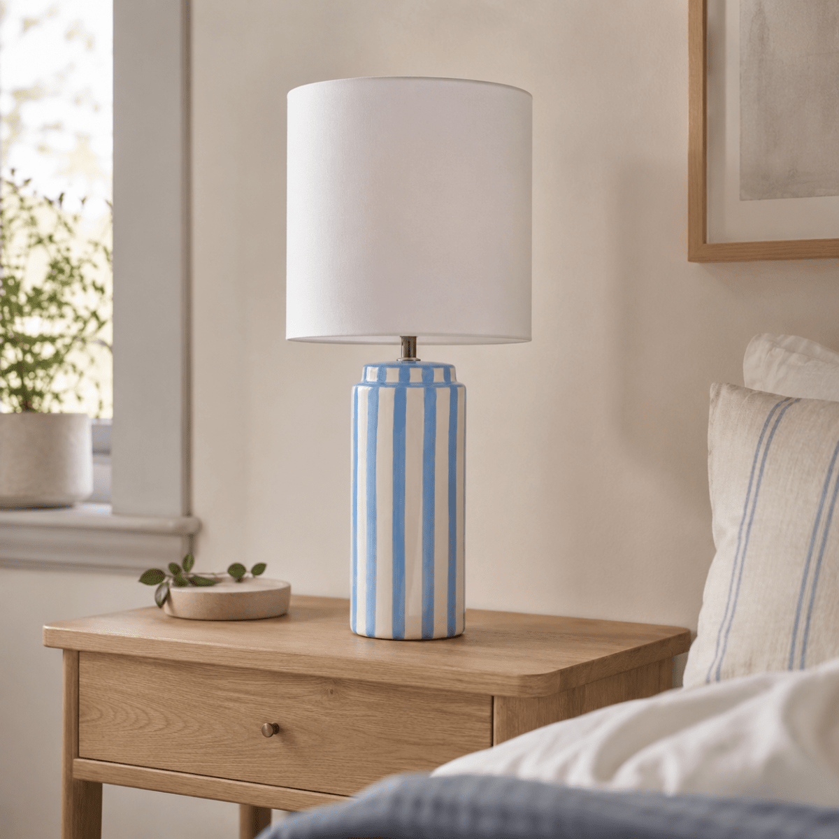 Faro 50cm Bleu clair/blanc lampe de table De Nordic Lighting - Son pied en c&eacute;ramique blanc cr&egrave;me est orn&eacute; de rayures bleu clair, cr&eacute;ant un style &agrave; la fois dynamique et harmonieux.