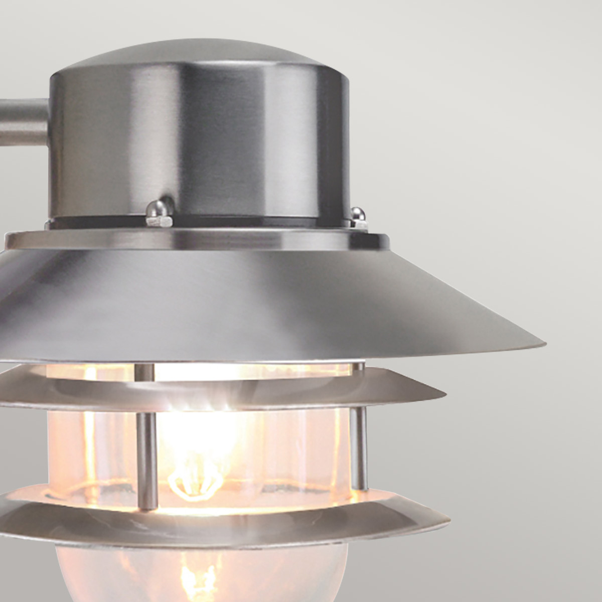 Copenhagen Ø22 Acier brossé lampe d’extérieur De Elstead Lighting - Tillverkad av rostfritt st&aring;l i borstad finish och glas, erbjuder den en h&aring;llbar och v&auml;dert&aring;lig konstruktion som passar perfekt f&ouml;r fasader, entr&eacute;er och uteplatser.