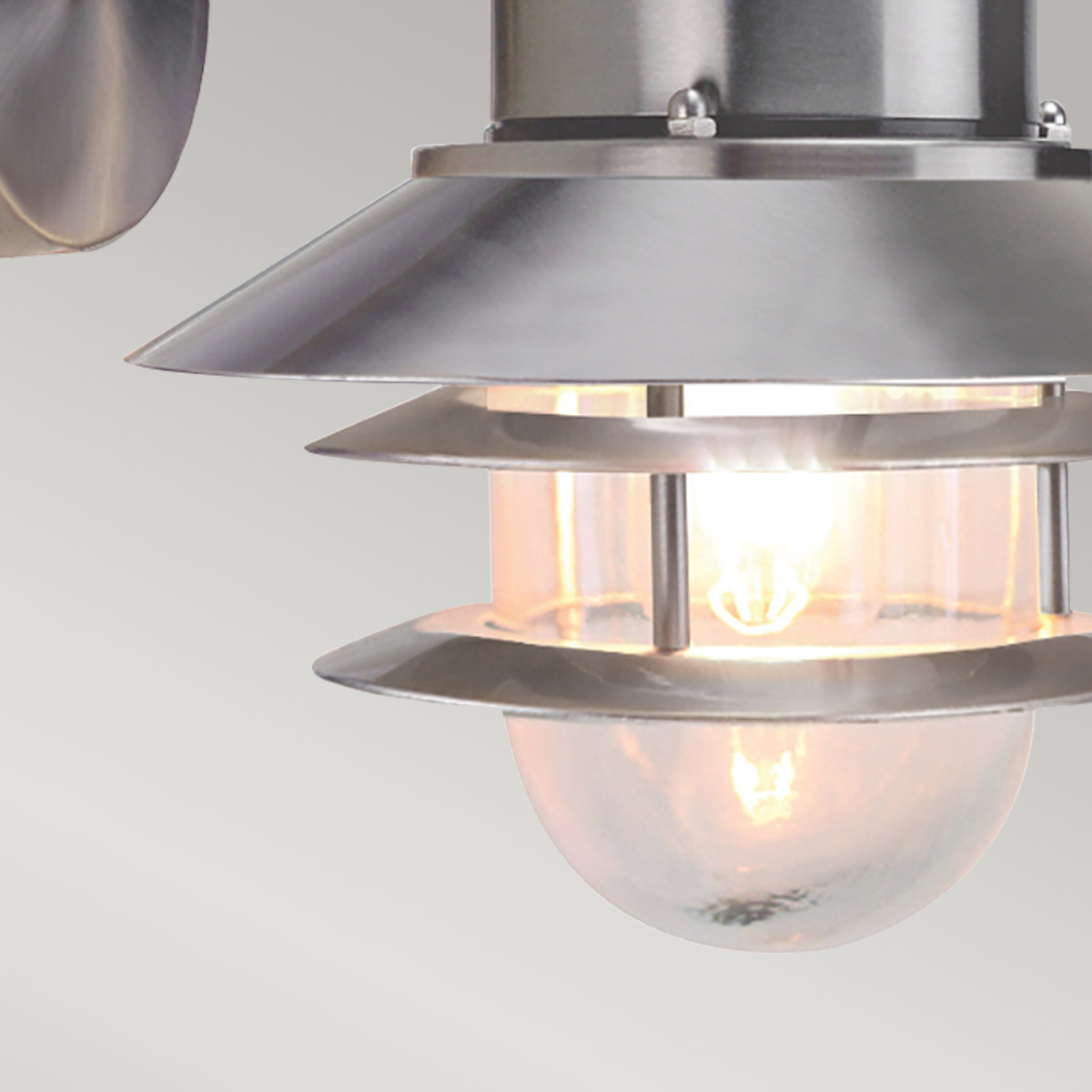 Copenhagen Ø22 Acier brossé lampe d’extérieur De Elstead Lighting - Tillverkad av rostfritt st&aring;l i borstad finish och glas, erbjuder den en h&aring;llbar och v&auml;dert&aring;lig konstruktion som passar perfekt f&ouml;r fasader, entr&eacute;er och uteplatser.