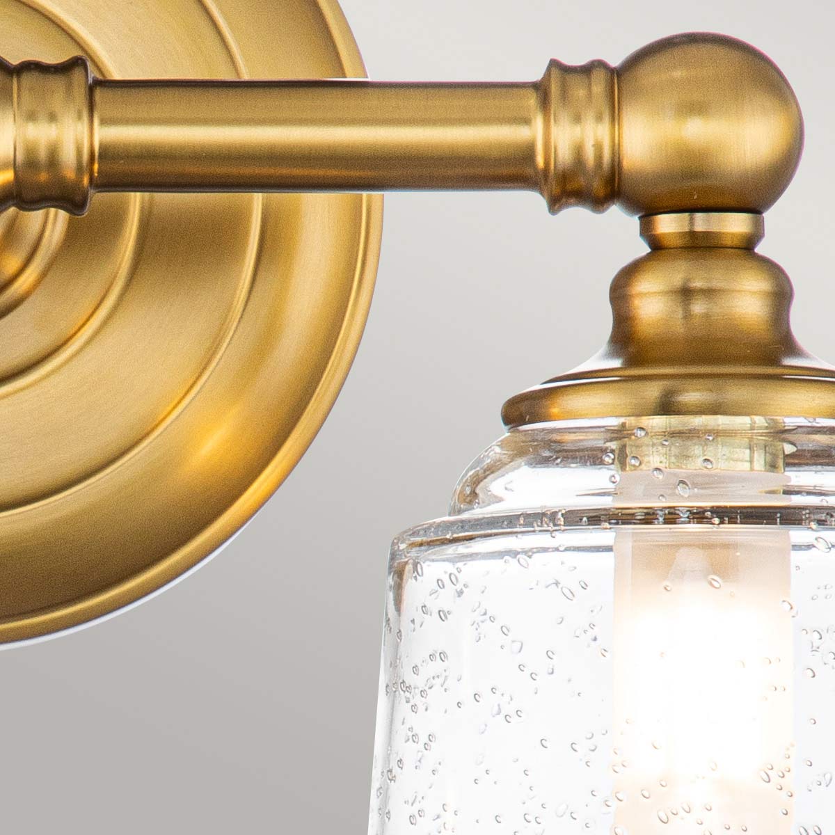 Huguenot Lake 33cm Laiton lampe de salle de bain De Elstead Lighting - Les élégants détails ronds et les cadres découpés à la main transmettent un sentiment d'artisanat traditionnel, tandis que le verre clair et texturé crée une lumière douce et invitante.
