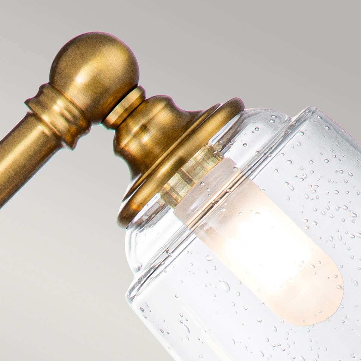 Huguenot Lake 53cm Laiton lampe de salle de bain De Elstead Lighting - Les élégants détails ronds et les cadres découpés à la main transmettent un sentiment d'artisanat traditionnel, tandis que le verre clair et texturé crée une lumière douce et invitante.