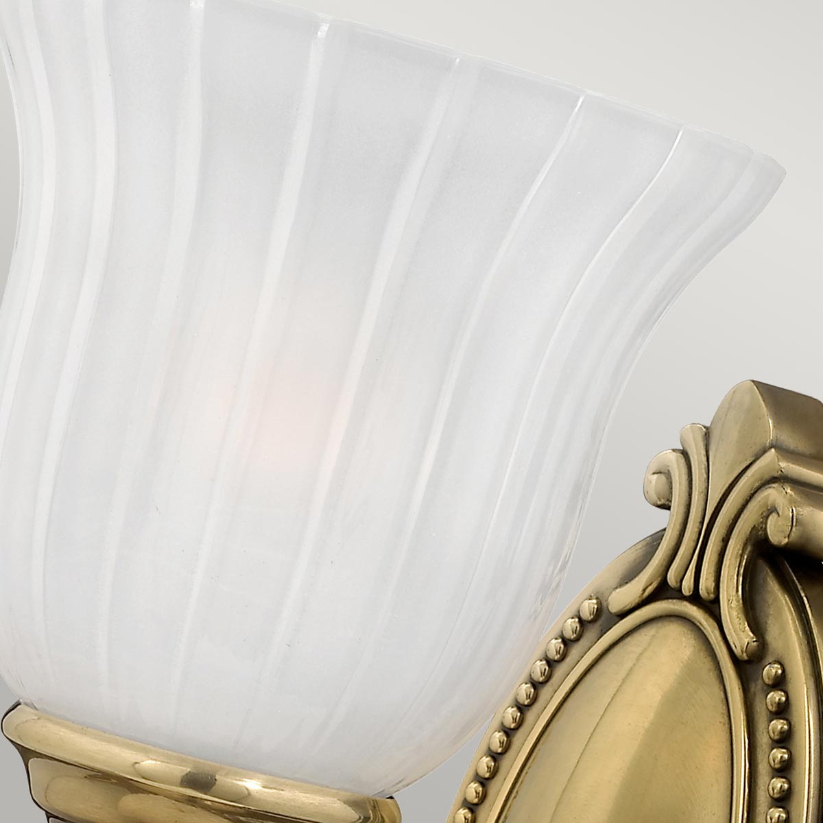 Francoise Ø15 Laiton lampe de salle de bain De Elstead Lighting - Il est doté d'un magnifique abat-jour en verre dépoli avec un design nervuré qui projette une lumière douce, et la base décorative en laiton ajoute une touche élégante.