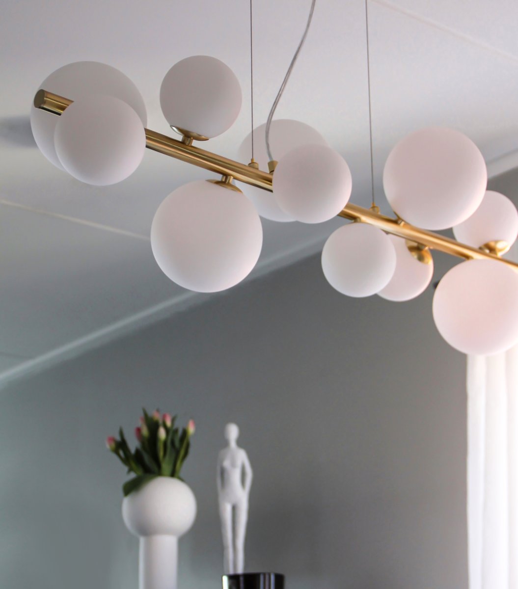 Molekyl 85cm Laiton mat suspension De Aneta Lighting - Plafonnier tendance de Molekyl en laiton mat avec 11 abat-jour en verre blanc de différentes tailles montés sur une tige de 85 cm de long.