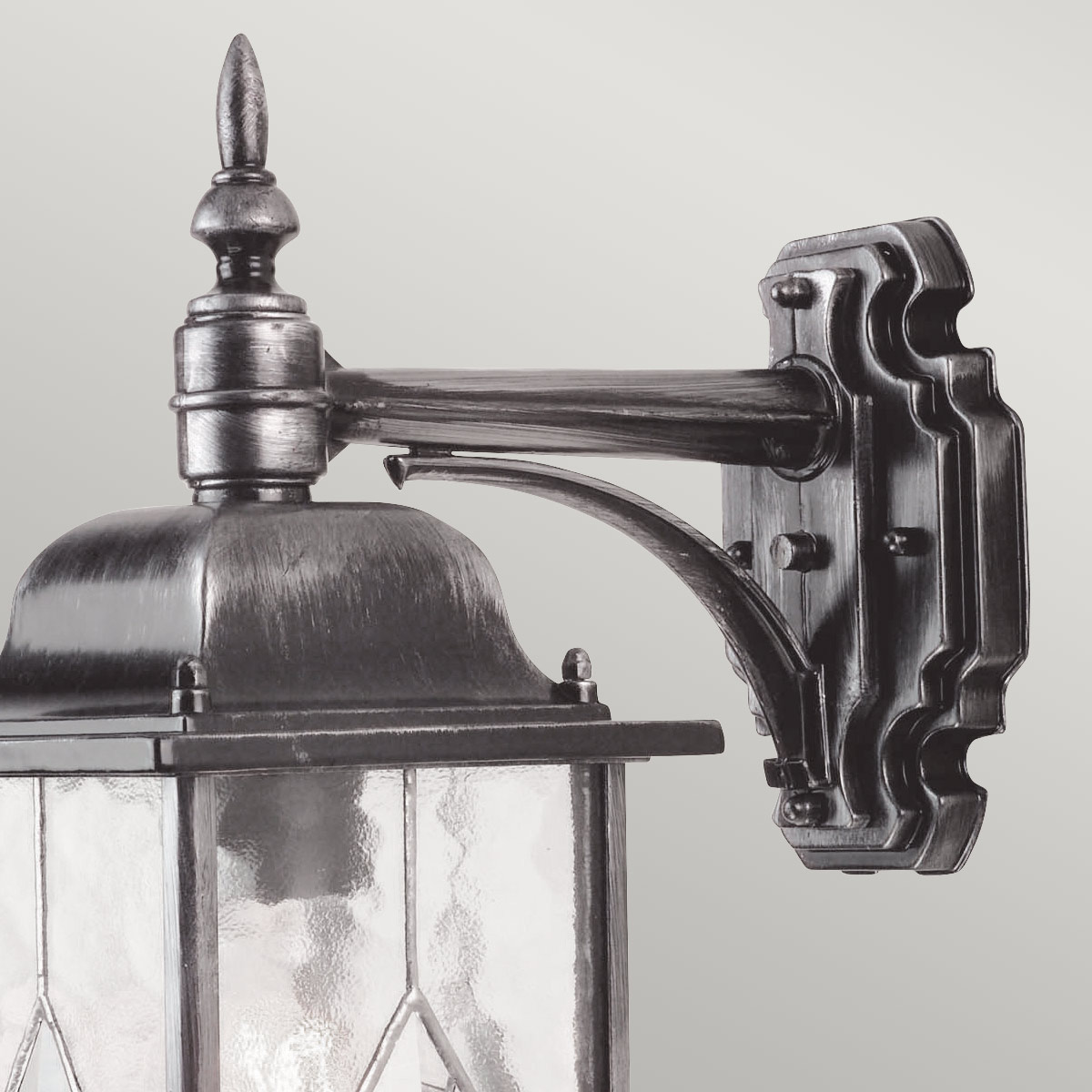 Wexford Argent lampe d’extérieur De Elstead Lighting - Wexford est une applique murale d'extérieur classique en aluminium, avec une élégante finition argent foncé et des éléments décoratifs en verre texturé façon vitrail.