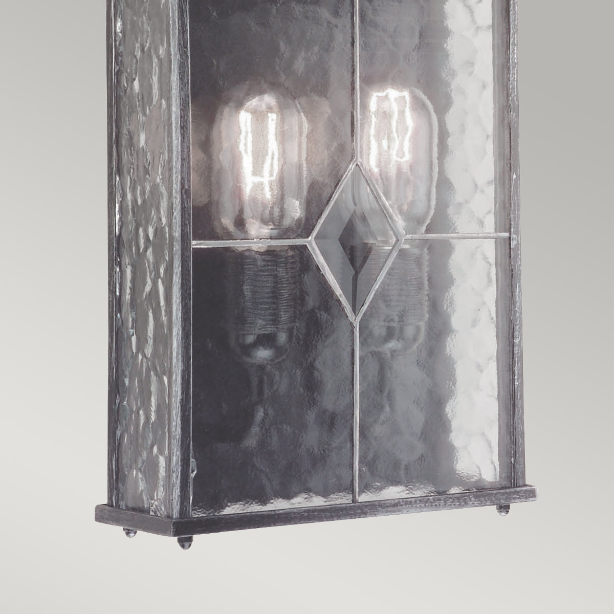 Wexford Argent lampe d’extérieur De Elstead Lighting - Wexford est une applique murale d'extérieur classique en aluminium, avec une élégante finition argent foncé et des panneaux de verre décoratifs à la texture de verre au plomb.
